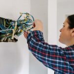 Mulher segurando embolado de fios saindo de um buraco na parede