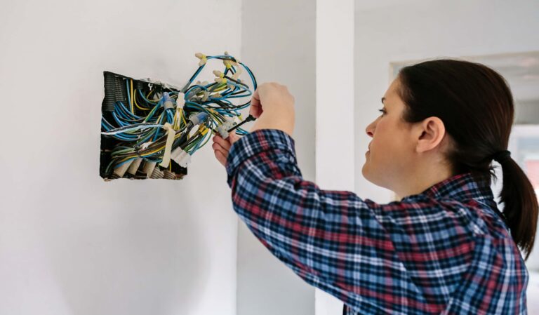 Mulher segurando embolado de fios saindo de um buraco na parede