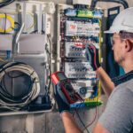 Homem medindo a tensão de energia em um painel elétrico