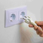 Pessoa colocando plug em tomada na parede