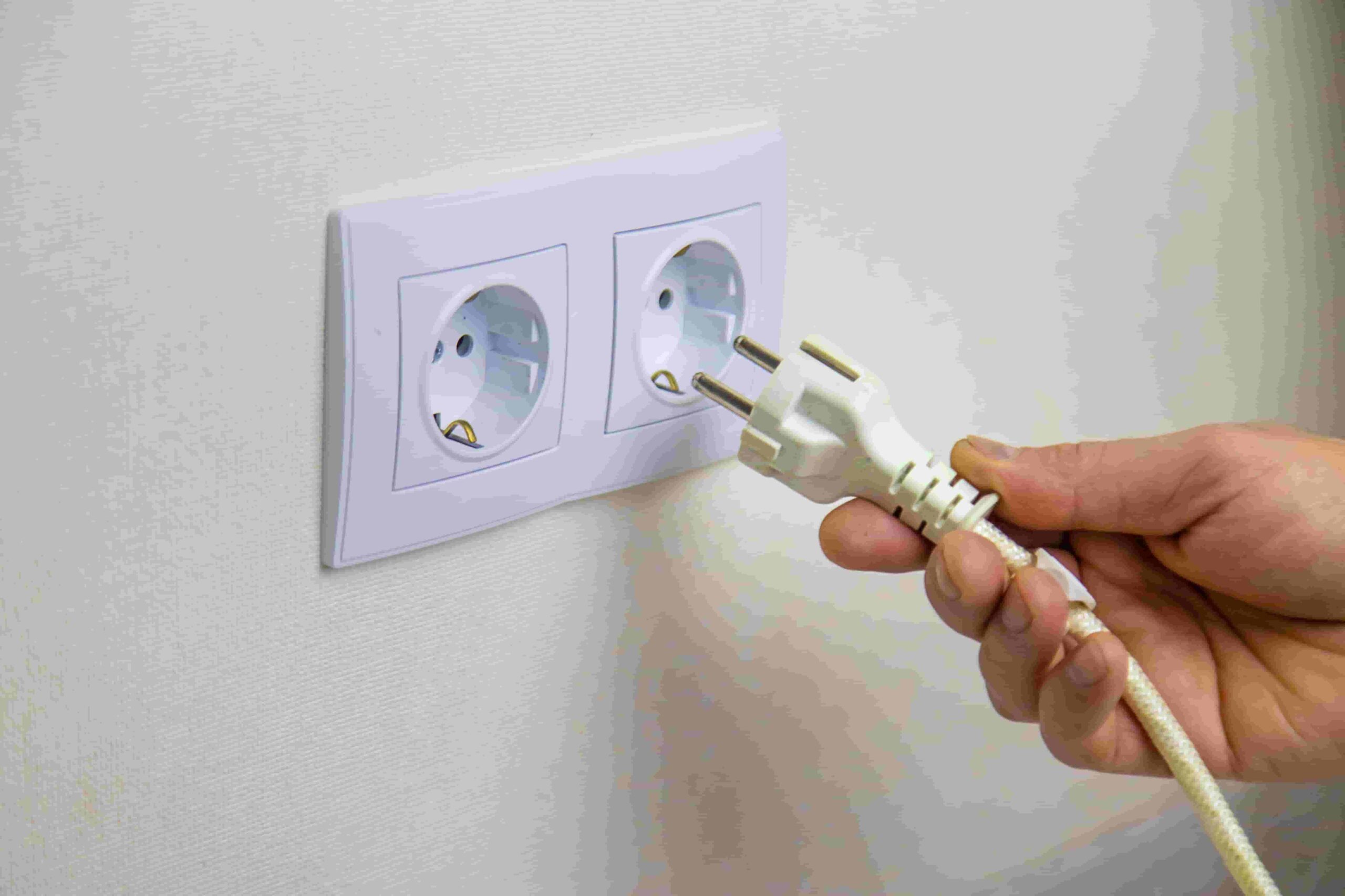 Pessoa colocando plug em tomada na parede